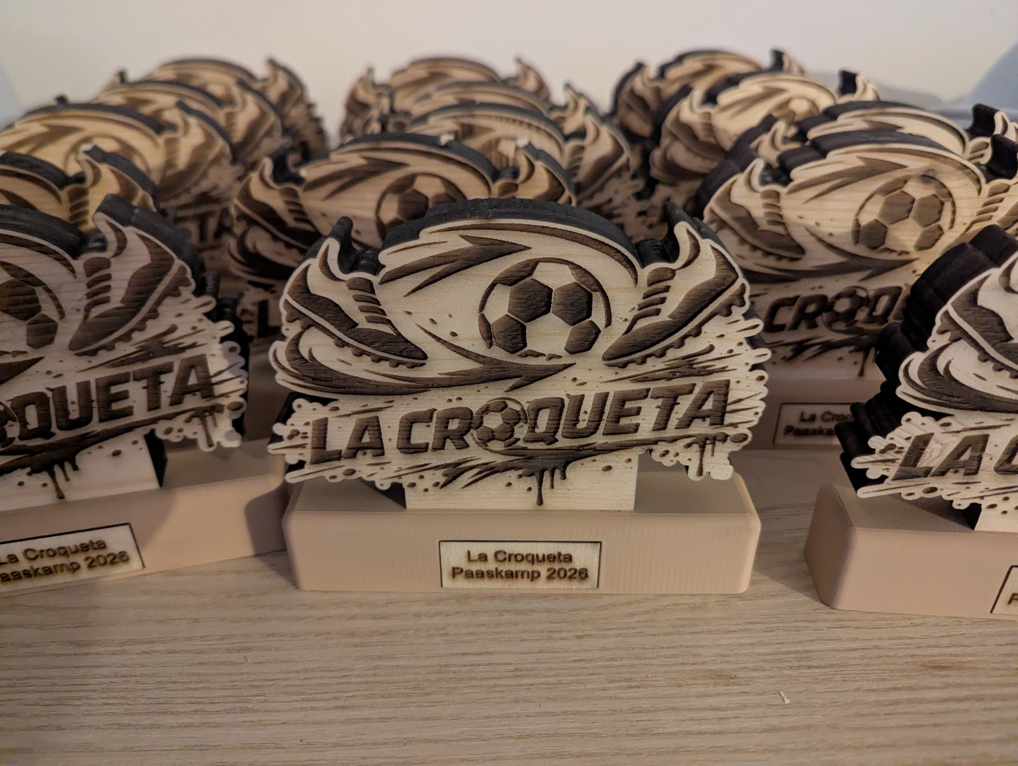 Trofeeën voor een voetbalkamp: gelasercut en gegraveerd logo op een 3D-geprinte basis met naamplaat.